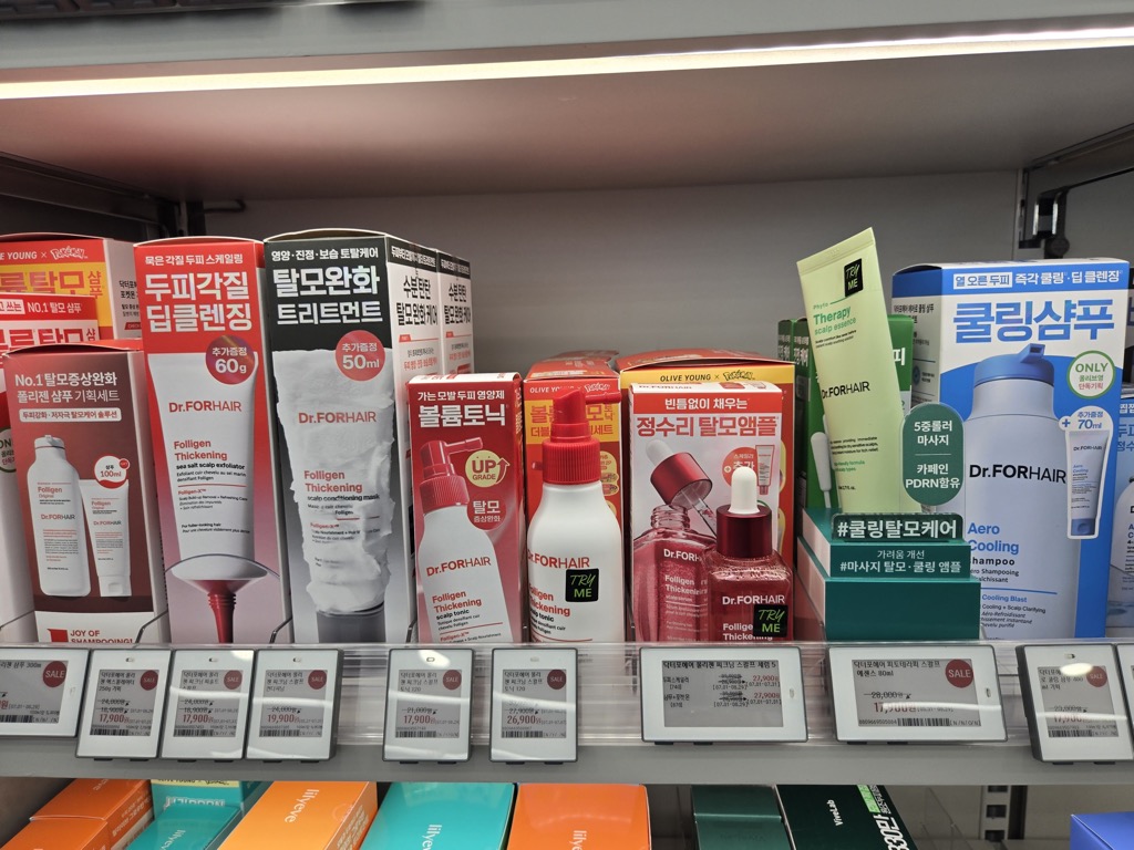 올리브영 닥터포헤어 두피·탈모 케어 라인 매대. 딥클렌징 샴푸, 트리트먼트, 토닉, 앰플 등이 진열되어 있고 세일 태그가 여럿 붙어 있다